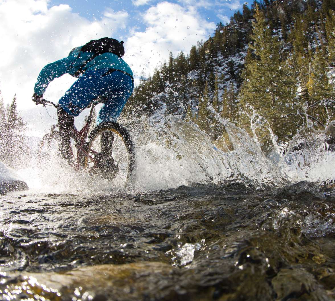 Un ciclista de montaña salpicando agua en un arroyo